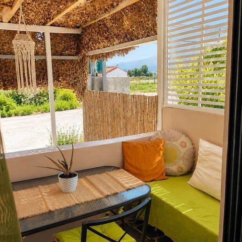 Enjoy relaxed outdoor living on the covered balcony, where comfortable seating and natural materials create an inviting space for morning coffee, reading, or unwinding after a day by the sea.