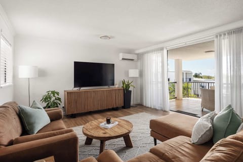 Light-filled living space with air conditioning and sliding doors opening to the balcony, creating seamless indoor–outdoor flow.