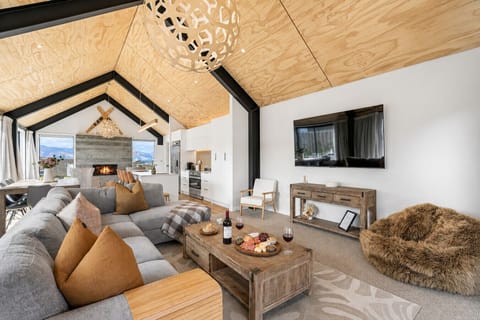 Cosy living room featuring a stunning stone fireplace, plush seating, and sweeping mountain views through floor-to-ceiling windows