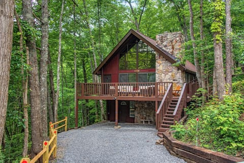 Nestled among towering trees, this charming A-frame cabin features a stone chimney, spacious deck, and serene forest setting accessible by a private gravel driveway.