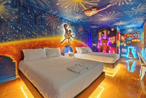 This themed room features vibrant murals inspired by the movie Coco with two comfortable beds and illuminated flooring.
