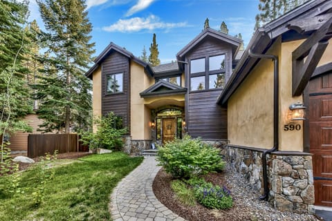 This charming mountain-style property sits nestled among towering evergreens, featuring stone and stucco accents with a welcoming front entrance and beautifully maintained landscaping on a quiet residential street.