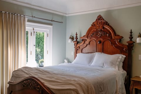 Elegant bedroom with carved wood bed and bright garden-facing doors