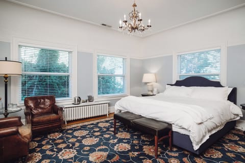Bright, elegant king bedroom with leather seating and garden views