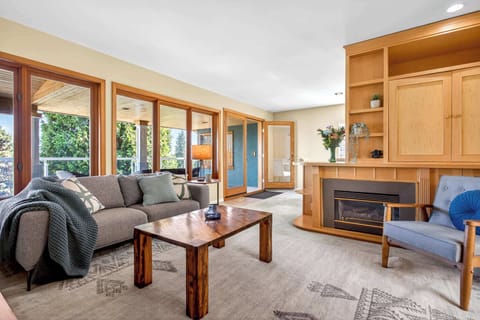 Bright and welcoming living room with large windows, a cozy fireplace, and comfortable seating in this North Vancouver vacation rental.