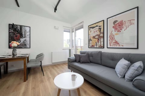 Bright and stylish living room with a comfortable sofa, coffee table, decorative artwork, and access to the balcony.