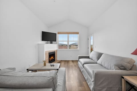 Cozy up in this bright living room with soaring vaulted ceilings, plush seating, and a warm fireplace. Mountain views frame your stay, inviting relaxation.