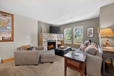 Cozy up in your spacious living room with a crackling stone fireplace, plush sectional seating, and natural light streaming through large windows—perfect for relaxing after a day of adventure.