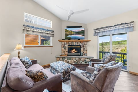 Relax in your cozy living room with plush seating, a warm fireplace, and mountain views through the patio doors—your perfect retreat after exploring nearby trails.