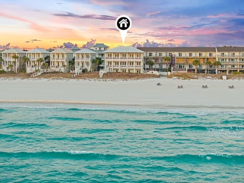 Beachfront property nestled on pristine white sands, where turquoise waters meet colorful skies at sunrise—a stunning coastal retreat in a beautiful natural setting.