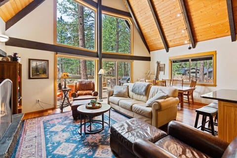 Vaulted A-frame living space with fireplace and forest views.
