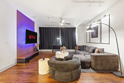 Cozy living space with accent lighting, large Smart TV, and stylish rounded furniture.