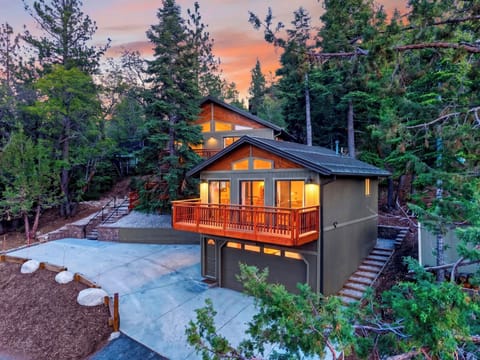 Twilight drone photography captures the cabin glowing warmly against the evening sky, showcasing the main garage structure.