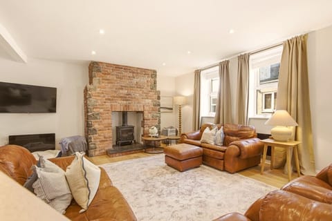 Living room with leather sofas, exposed brick fireplace and wood burner.