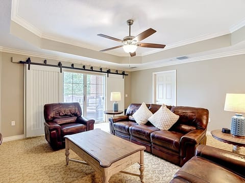 Spacious living room with leather seating, coffee table, and large windows providing plenty of natural light.