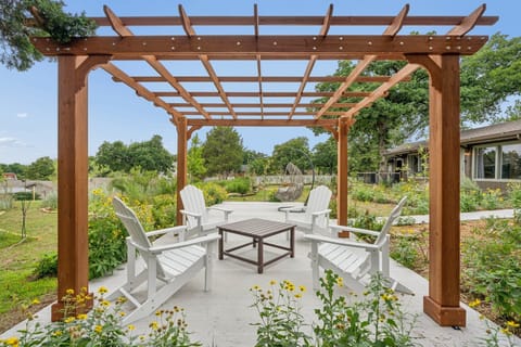 Enjoy a quiet moment outside with shaded seating, greenery, and a calm view of the backyard.