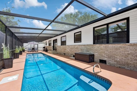 Out back, the entire backyard and side yard are enclosed within a full screened structure — a 40-foot lap pool, outdoor dining, propane grill, chaise lounges, and a wicker couch, all in complete privacy.