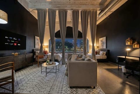 Bags down. City lights up. Lamp glowing. Crew gathering.  Your moody downtown loft — queen beds, private bunk suite, and room for the whole crew.