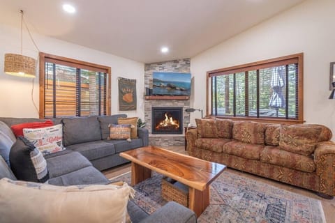 Spacious great room with vaulted ceilings, living area, gas fireplace, 50 inch SmartTV, dining area, kitchen and direct access to front deck.