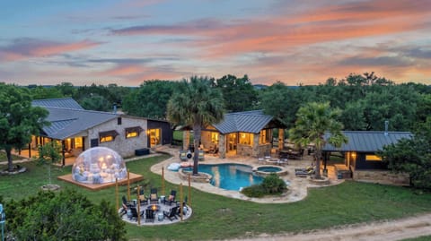 Experience the ultimate getaway at this stunning property, featuring a private swimming pool, a cozy fire pit area, and a unique outdoor dome for stargazing under the beautiful evening sky.