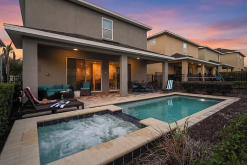Relax by the private pool and hot tub at this modern home during sunset.