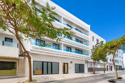 A modern white apartment building with stylish balconies on a sunny city street.