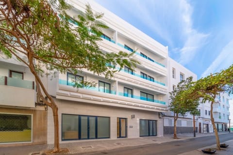 A modern white apartment building with stylish balconies on a sunny city street.