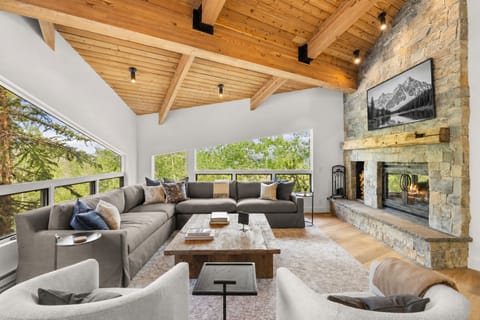 The top floor primary living room with wood-buring fireplace, angled windows, and smart TV with cable.
