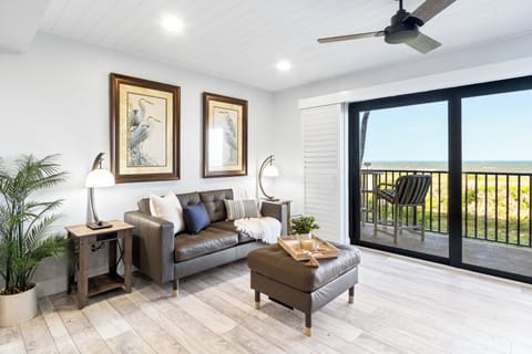 Bright & airy living room with sliding glass doors that lead to an outdoor balcony with ocean view