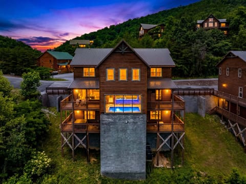 Spacious luxury cabin exterior at dusk featuring multiple decks, mountain scenery, and upscale Smoky Mountain vacation rental accommodations in Tennessee.
