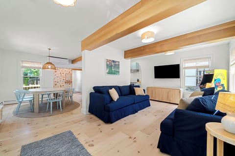 Bright open living space with exposed beams, hardwood floors, and coastal charm