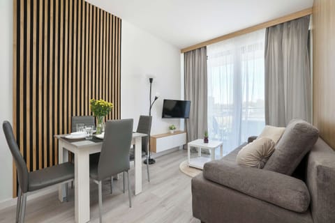 Bright and modern living room featuring a comfortable sofa, Smart TV, and elegant wood-accent interiors.