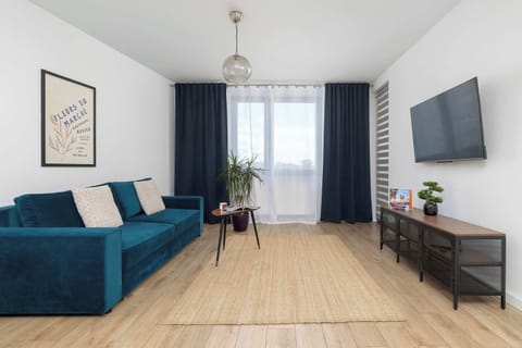 A spacious lounge area featuring a blue sofa, a TV, and modern furnishings. The open layout provides plenty of room to relax and unwind.