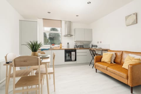 Open-plan living, dining, and kitchen area designed for relaxing and socialising. Features a comfortable two-seater sofa, Smart TV, four-seater dining table, and a fully equipped kitchen with everything needed for a comfortable stay.