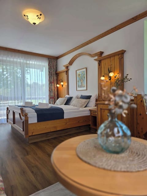 Rustikales Schlafzimmer mit gemütlichem Doppelbett, hochwertiger Holzeinrichtung und warmer Beleuchtung im alpinen Stil.