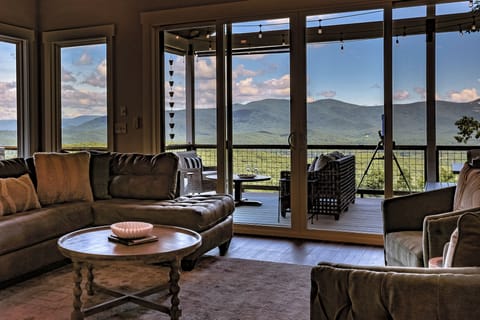 Living room wall of windows opens to Blue Ridge mountain and sunset views