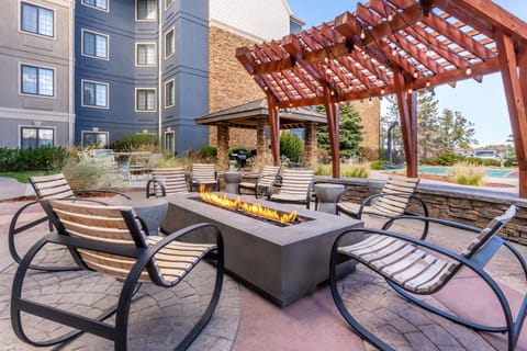 Outdoor courtyard firepit with modern rocking chairs and string lights — evening socials run Mon–Wed