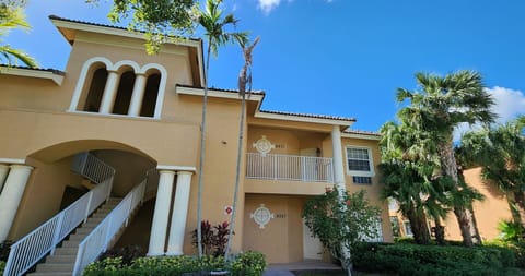 Exterior view of the building with covered entryways, tropical landscaping, and bright Florida-style architecture.