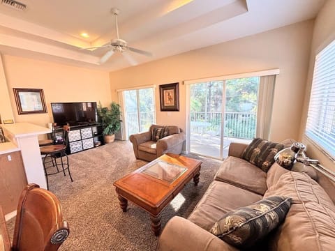 Comfortable living area with cozy seating, high ceilings, large TV, and sliding glass doors that open to the private balcony.
