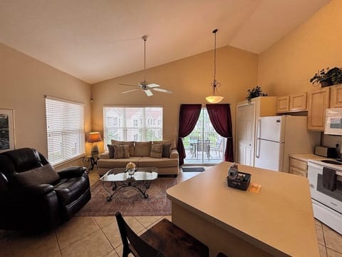 Open-concept living, dining, and kitchen area with comfortable seating, tile flooring, and plenty of natural light.