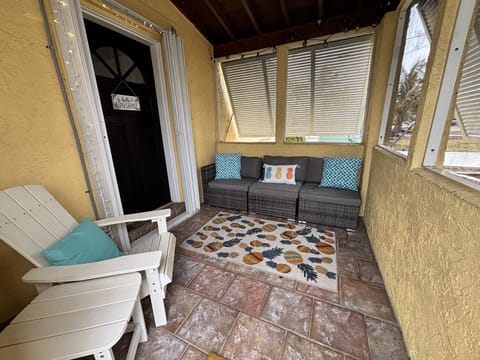 Covered front porch with outdoor seating, tropical accents, and a relaxed beach cottage feel.