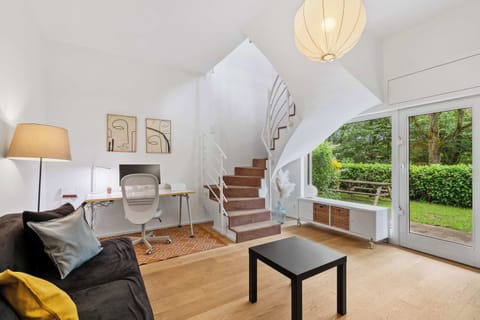 Bright living area with cozy seating, warm natural light, and direct views toward the green outdoor space