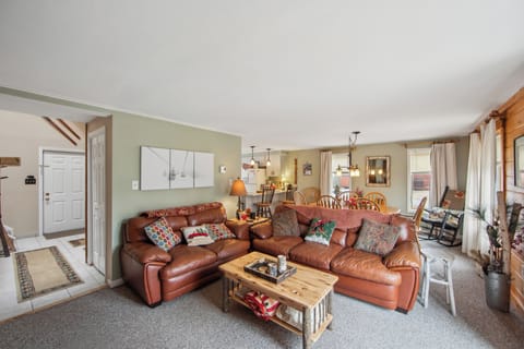 Warm, inviting open-concept living area featuring comfortable leather seating and a cozy, rustic ambiance.