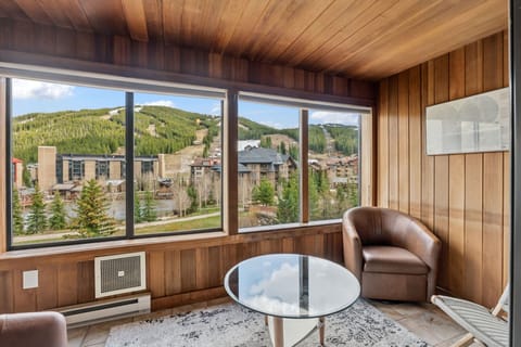 Your private retreat showcases panoramic mountain and village views through expansive windows, framed by warm wood paneling. Sink into the leather armchair with coffee and soak in ski slopes and alpine scenery stretching before you.