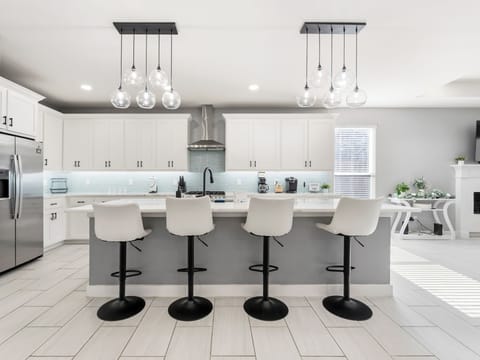 Settle into your private chef's kitchen, where sleek white cabinetry meets a spacious island with seating for four. Natural light floods the space, perfect for morning coffee or evening meals together.