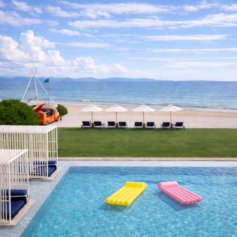 Oceanfront pool, cabanas, and loungers with direct sandy beach access