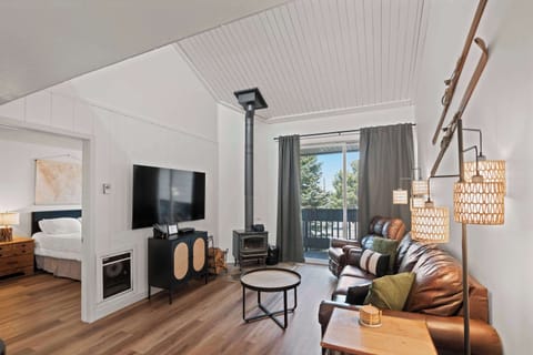 Cozy cabin living room with fire, leather, and balcony.
