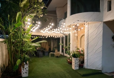 Cozy garden patio with string lights, turf lawn, and lush plants