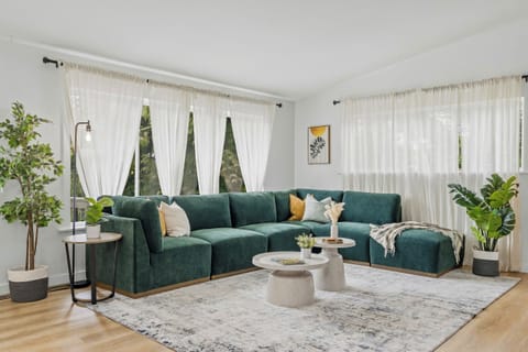 Sun-soaked and serene - this lush, plant-filled living room with a dreamy green 