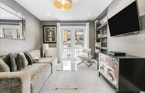 Bright living room with a comfy sofa, balcony access, and TV